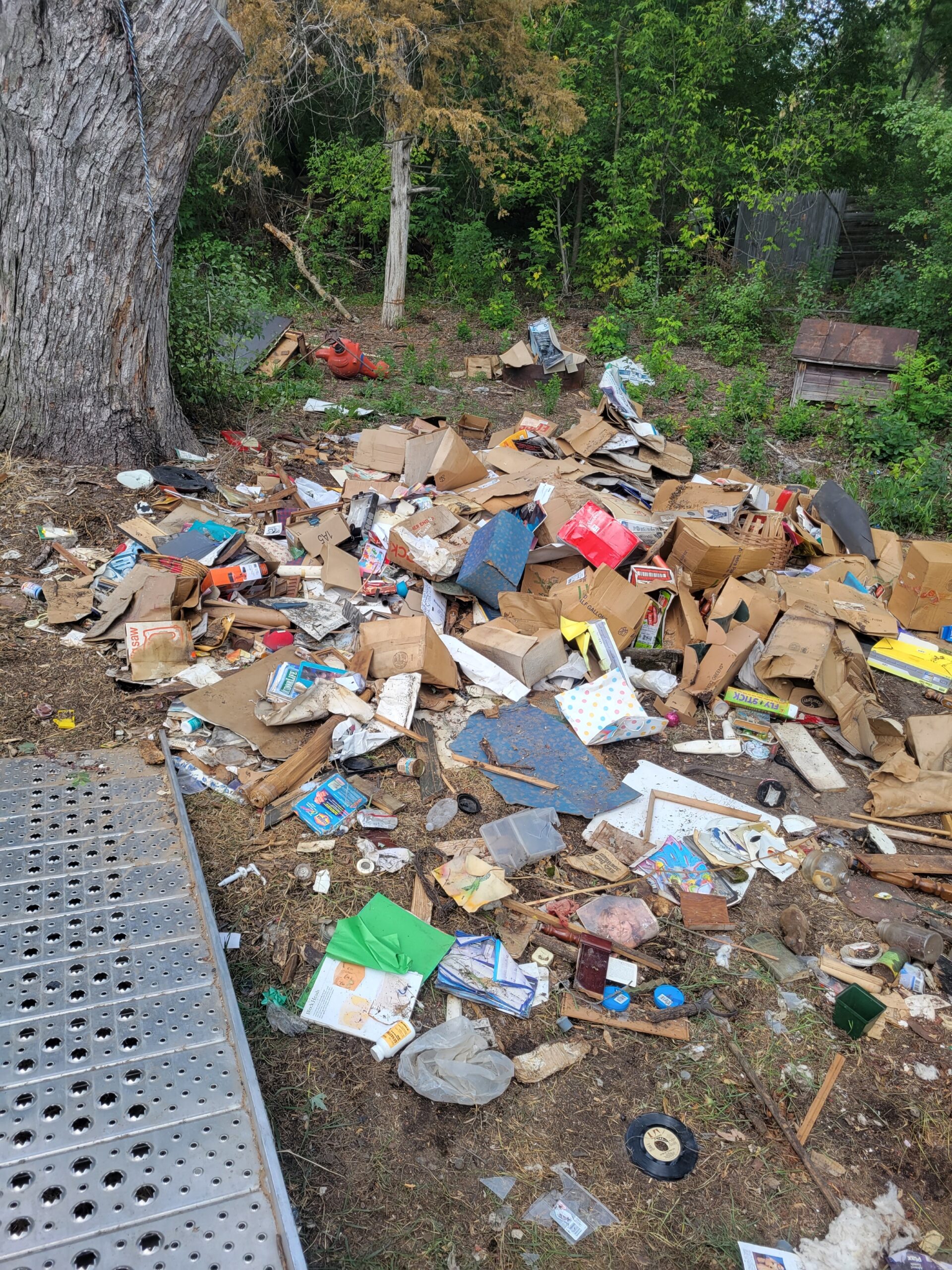 A yard filled with trash and debris. Foreclosure clean out services offered.